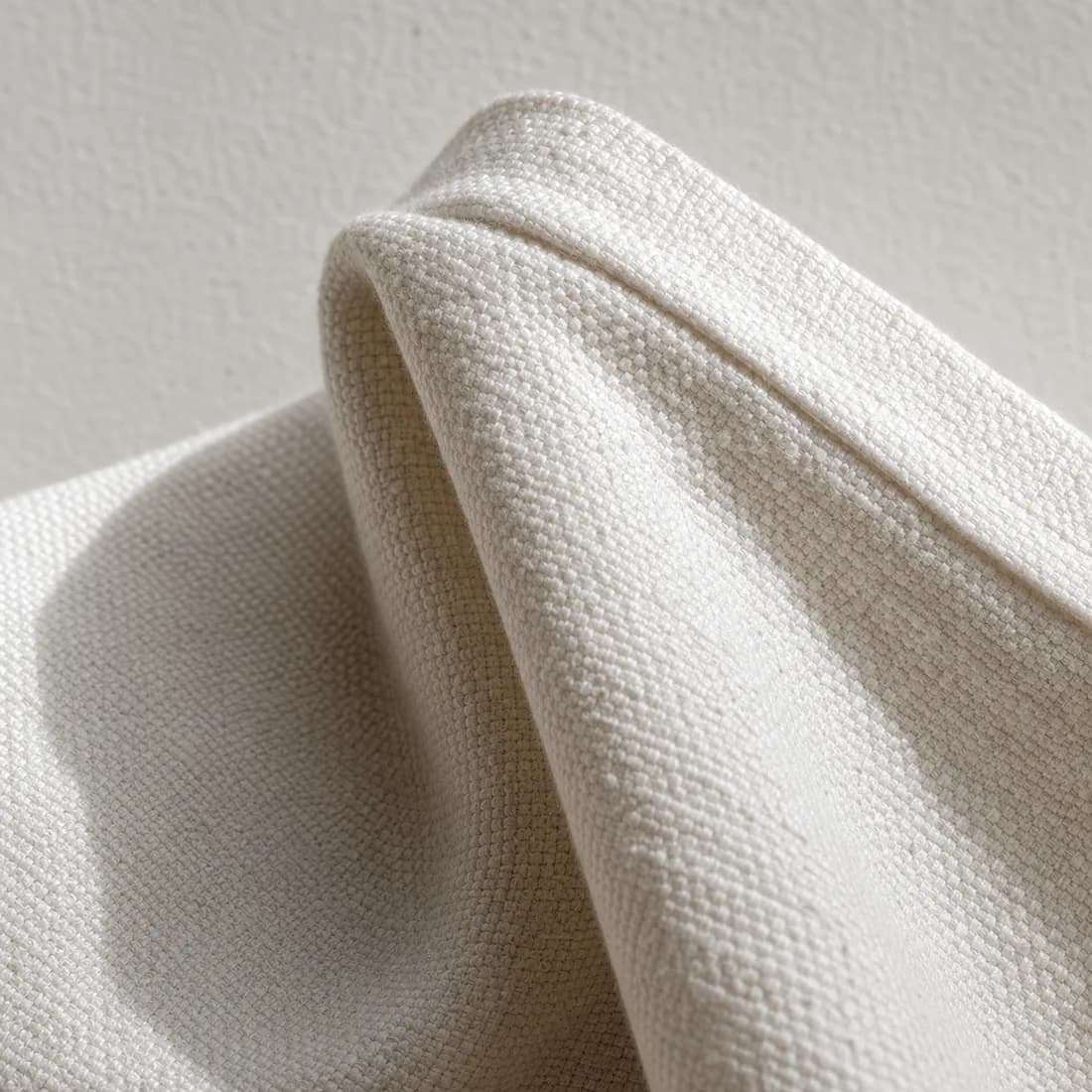 Woven cotton at extreme magnification, raking light picking out every thread of the weave