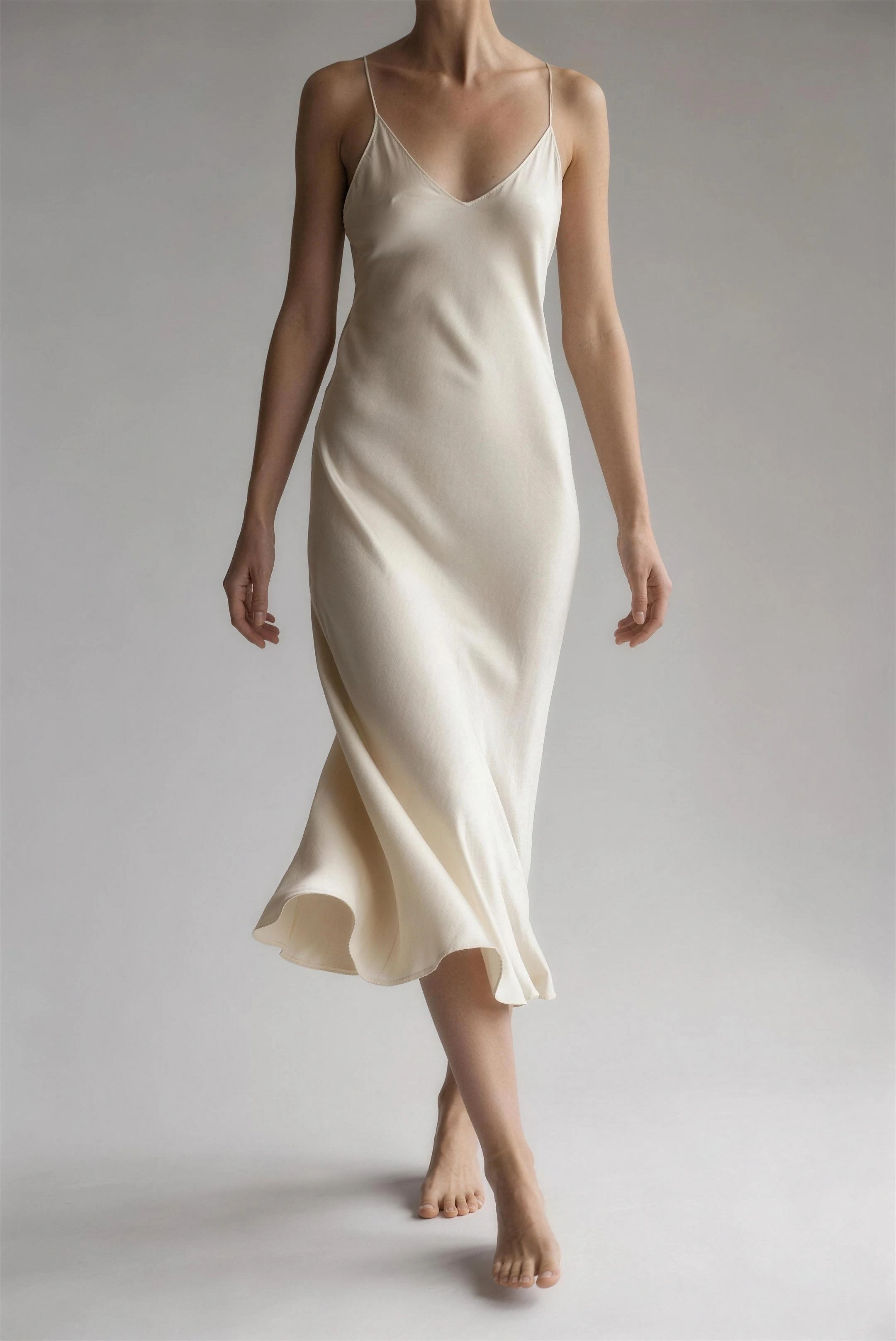 Bone silk ines dress caught mid-step, the bias-cut skirt swinging to one side